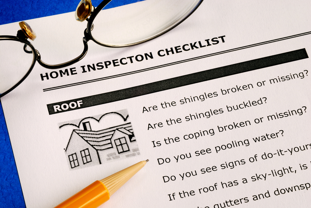 Home inspection checklist with a pencil and magnifying glass, focusing on roof condition.