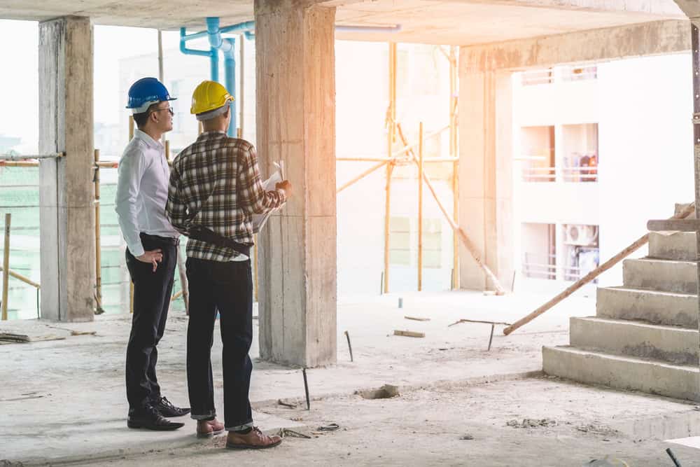 Two construction workers discussing blueprints at a building site.