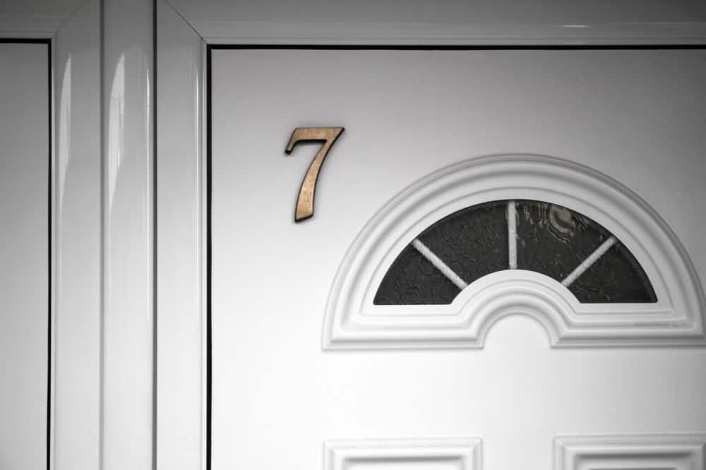 The number 7 adorns a classic white door with intricate glass detailing.