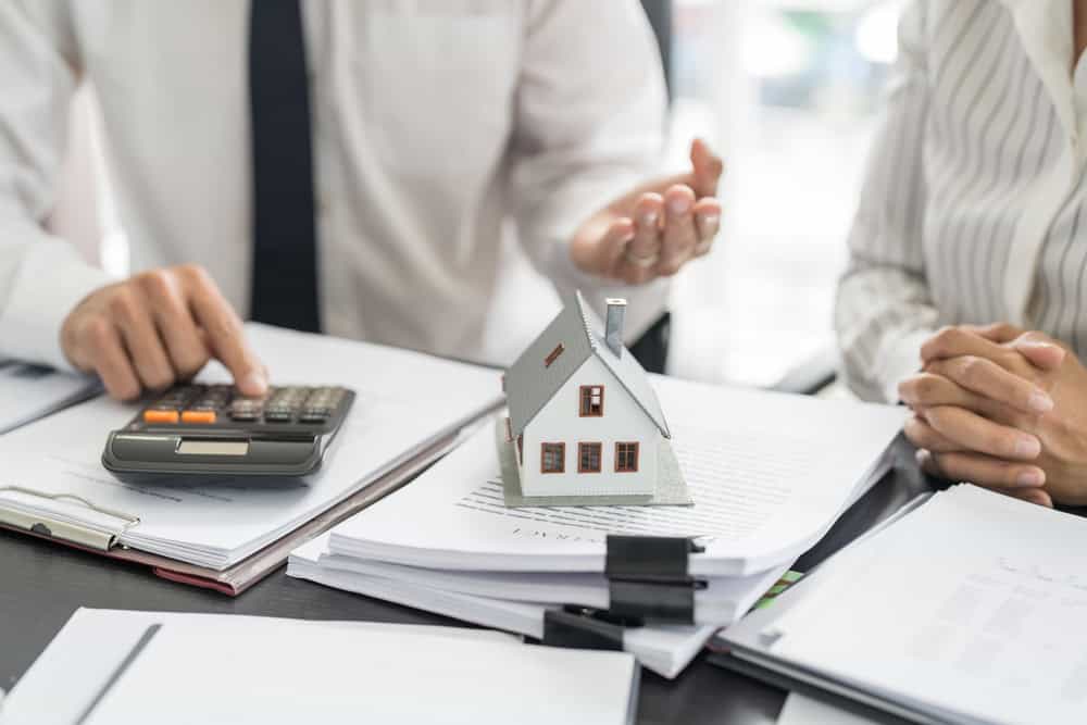 Calculating the cost of homeownership with a model house and calculator on the table.