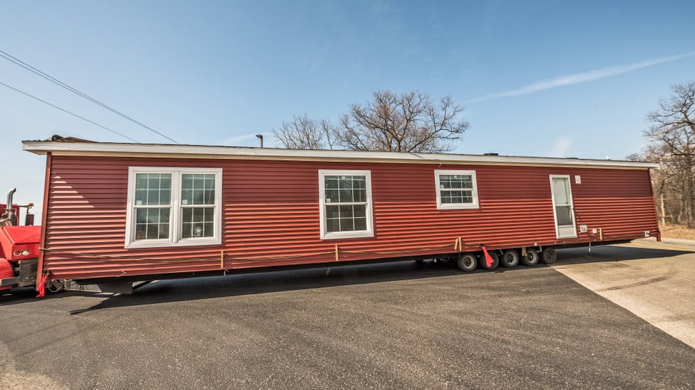 A vibrant red mobile home ready to hit the road under a clear blue sky.