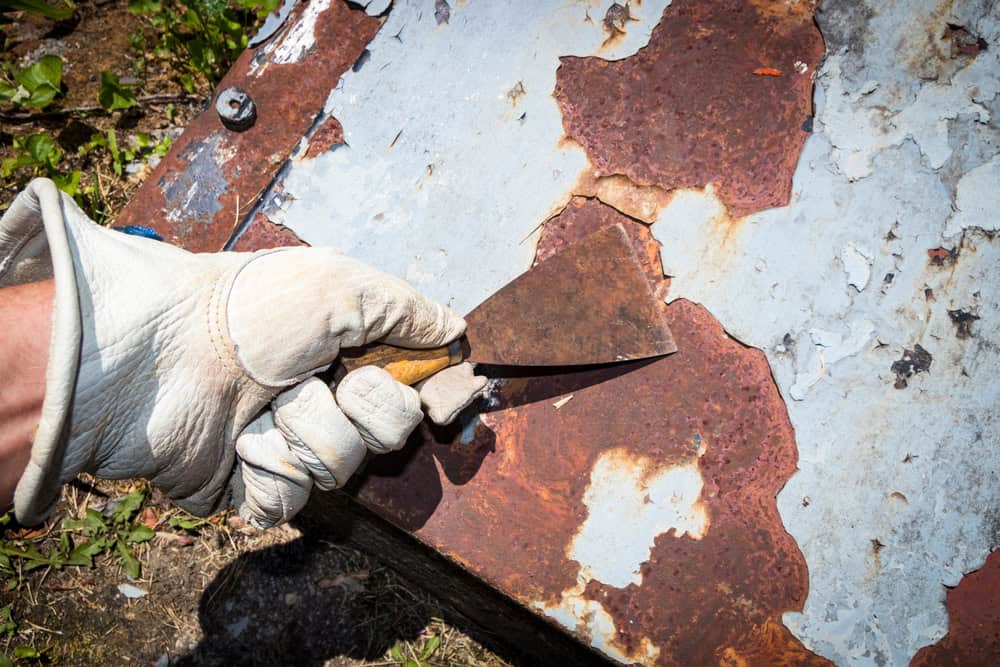 Scraping away rust and paint from metal doors