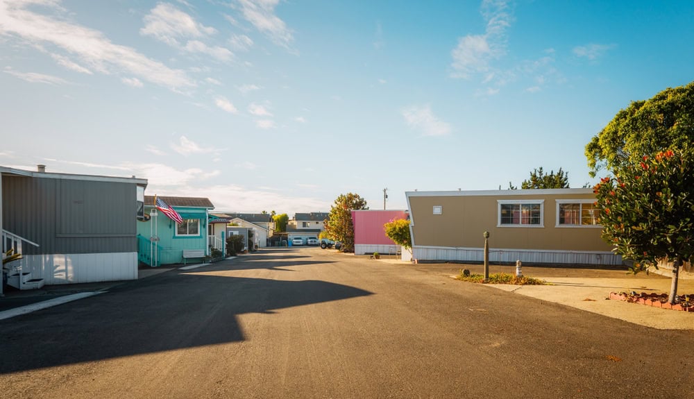 A serene mobile home park under a clear blue sky, with colorful homes and a quiet street.
