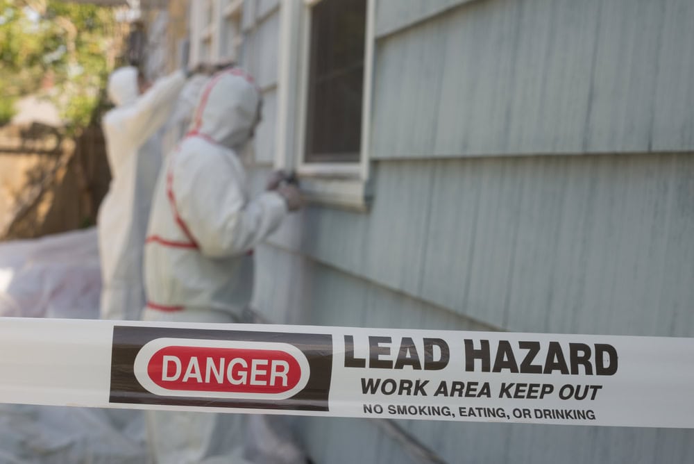 Workers in protective suits handle a lead hazard area, emphasizing safety and caution.
