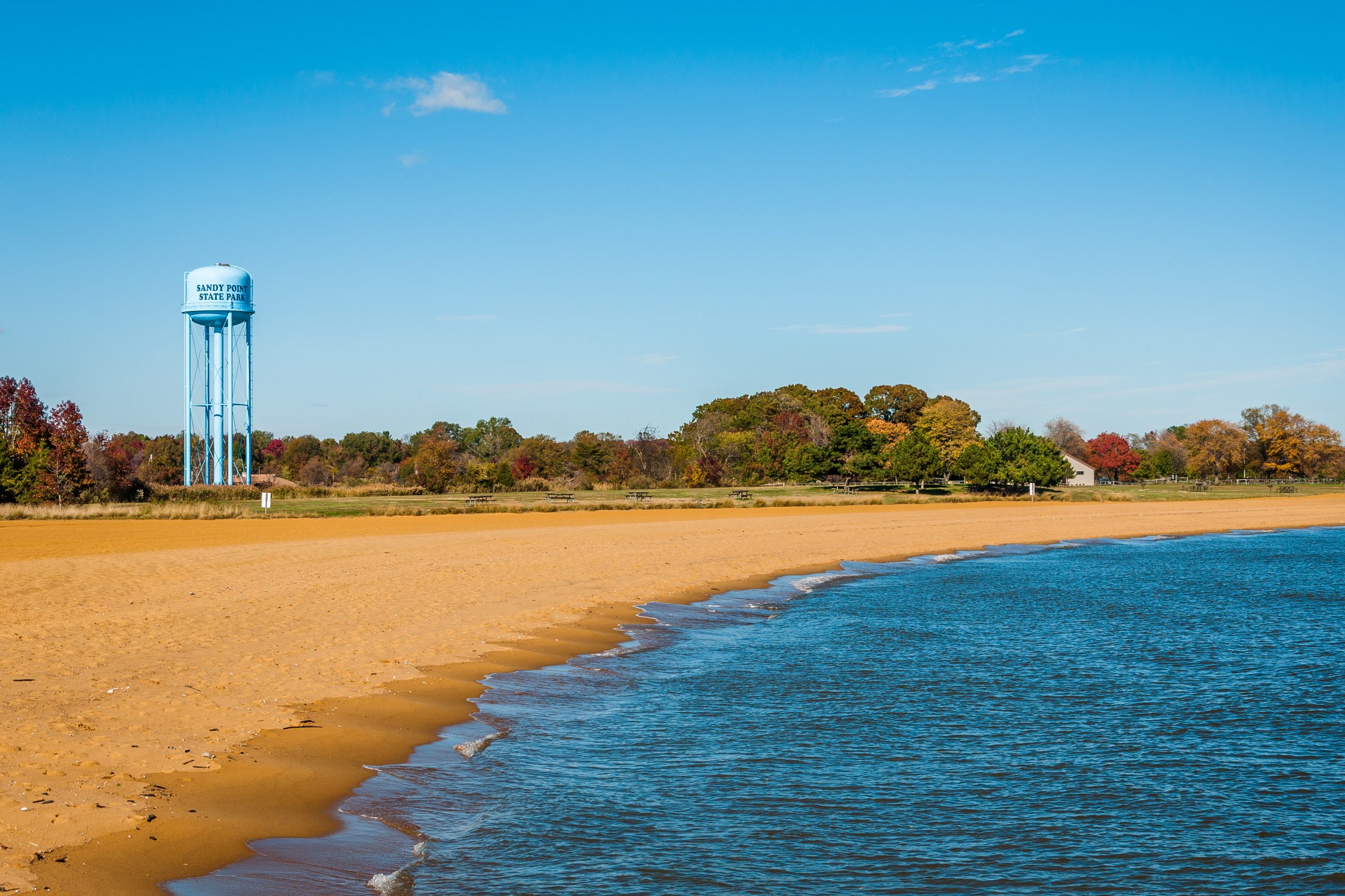 A peaceful view of Sandy Point State Park, Maryland, with its iconic water tower and a quiet beach.