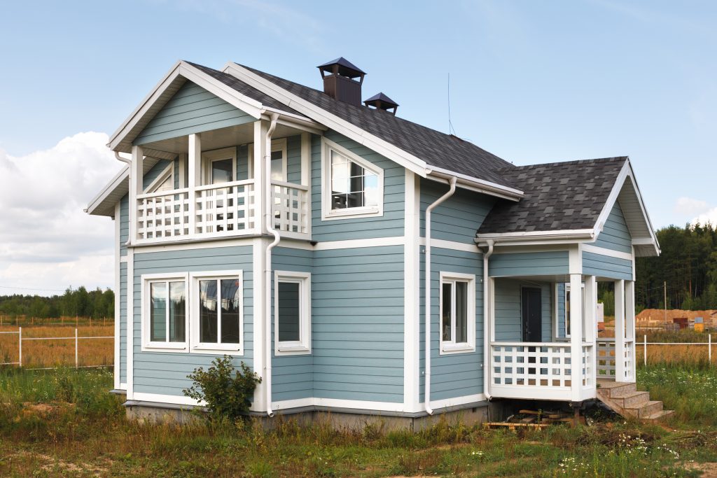 Charming blue country house with white trims, nestled in a serene rural landscape.