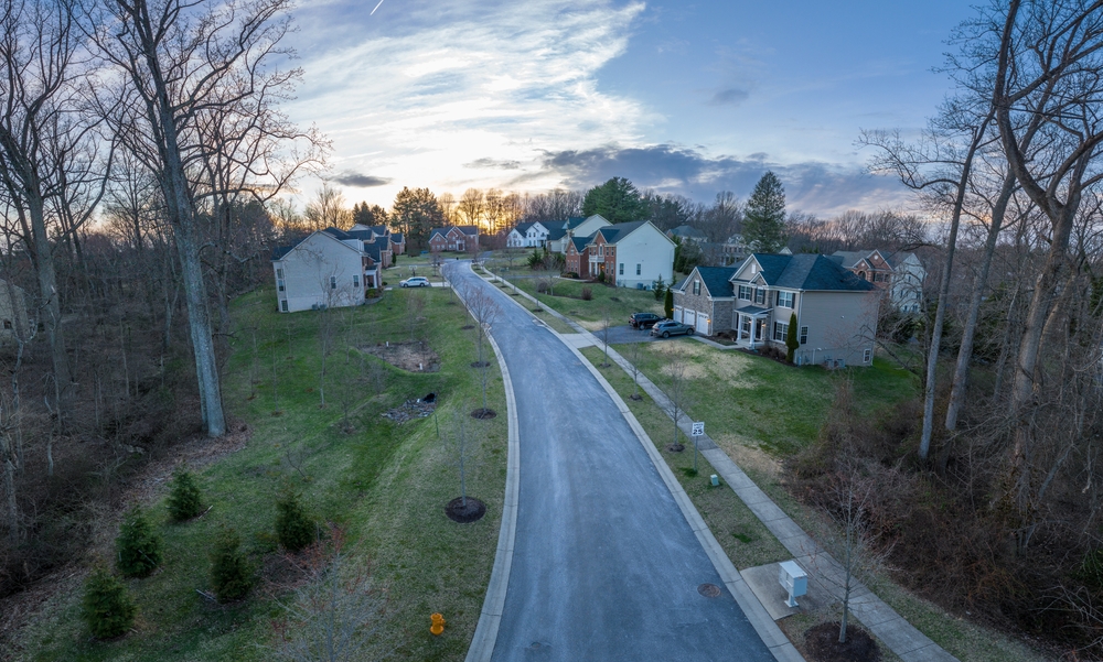 A peaceful suburban street stretches into the sunset, flanked by charming houses and winter-bare trees.