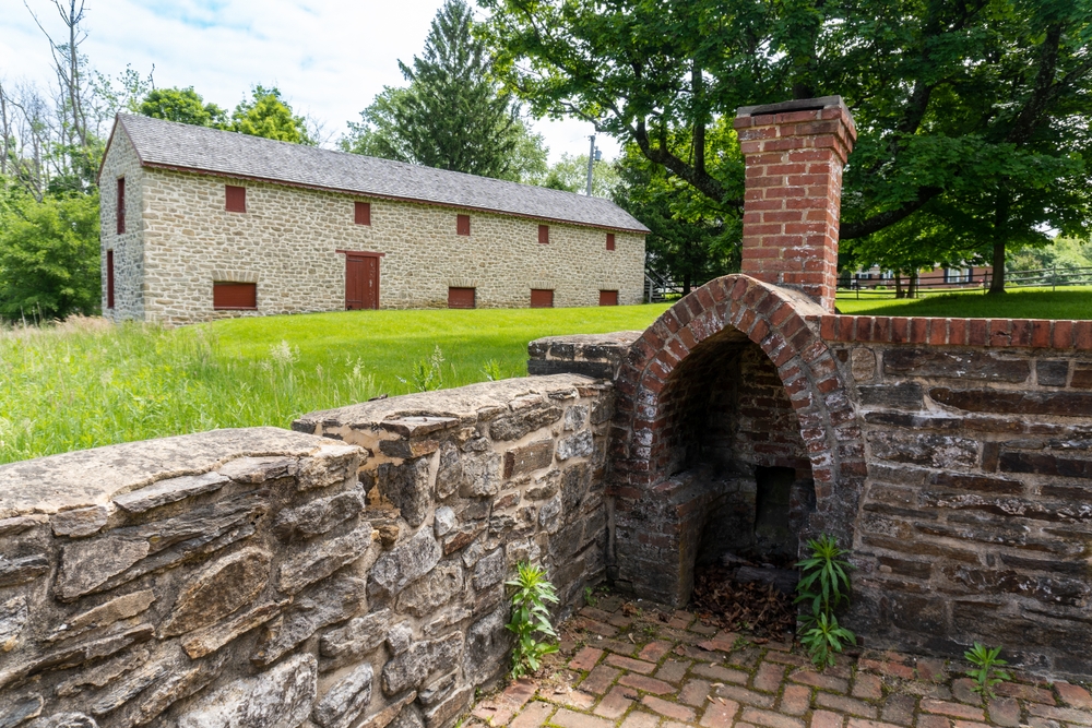 Historic stone barn and brick fireplace tucked in a grassy field, remnants of a bygone era.