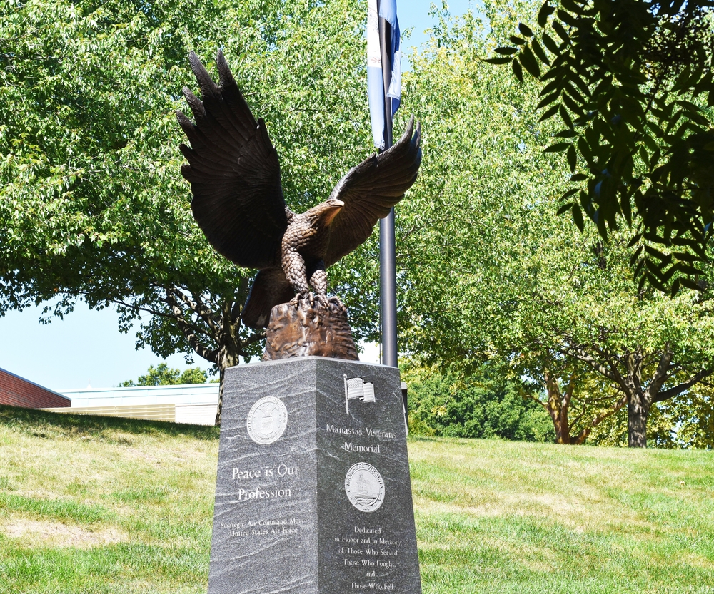 A bronze eagle statue stands tall at the Manassas Veterans Memorial. "Peace is Our Profession" reads a plaque on the pedestal.