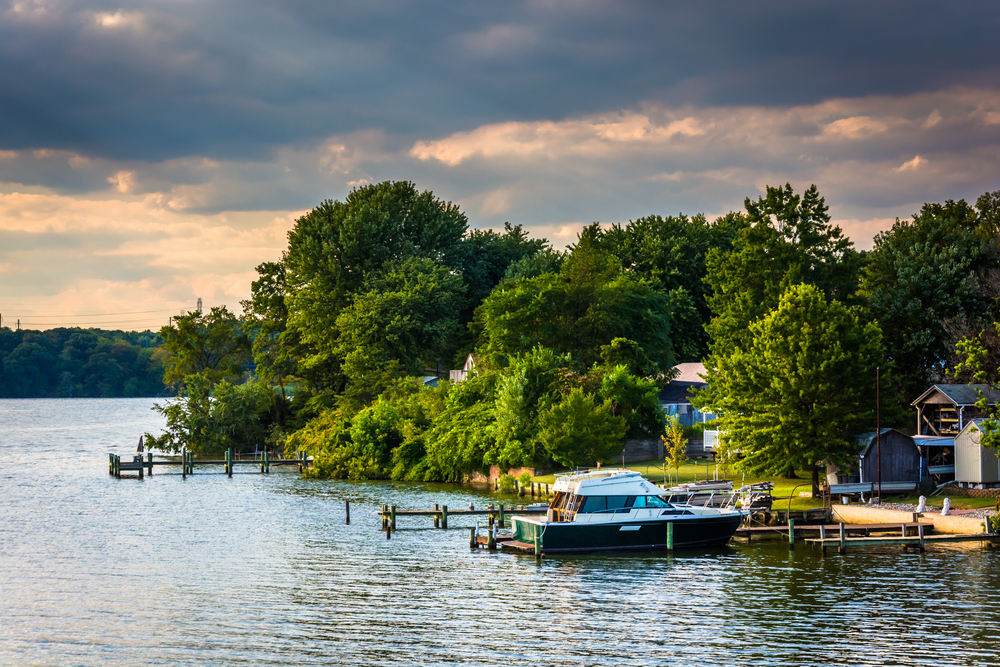Tranquil lakeside at twilight, with a boat docked and serene greenery hugging the shoreline.