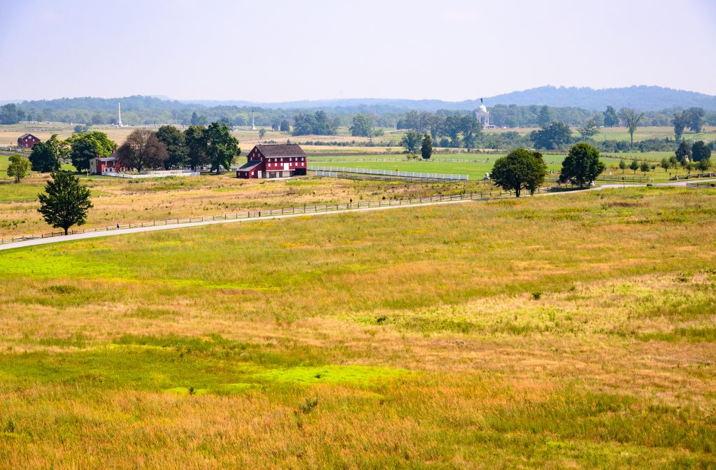 Expansive fields at Gettysburg National Military Park, with historic red barns dotting the serene landscape.