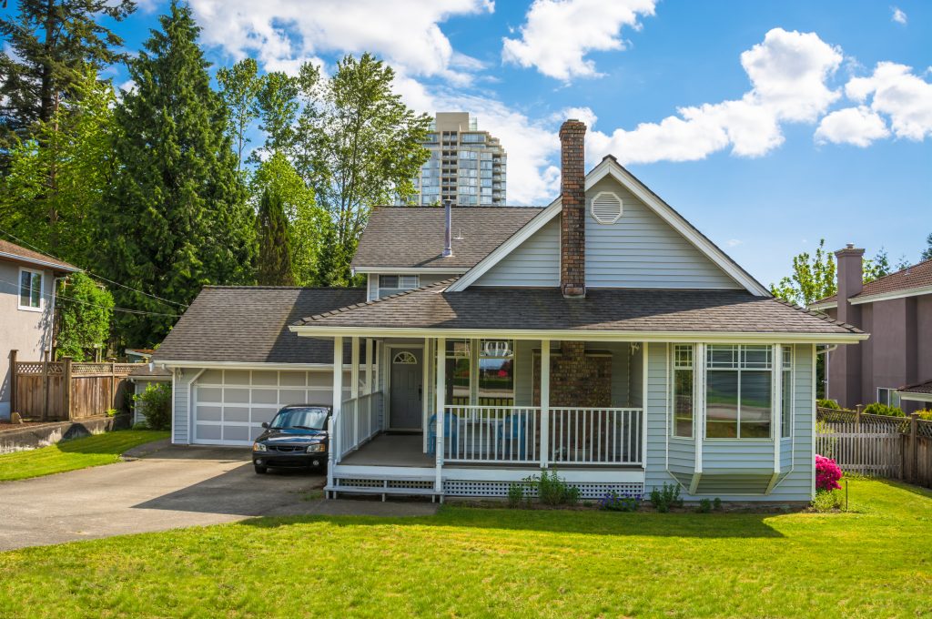 Charming suburban home with a spacious front yard and cozy porch, nestled amidst lush greenery and cityscape views.