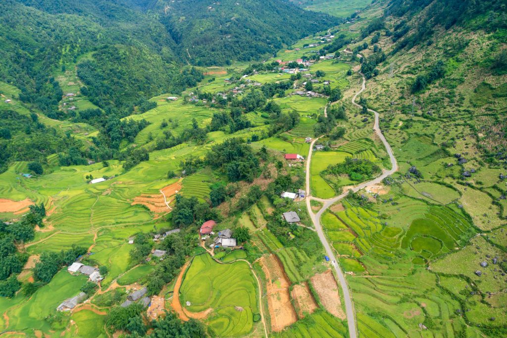 Aerial view of lush terraced rice fields and rural villages nestled in the verdant hills, creating a breathtaking landscape.