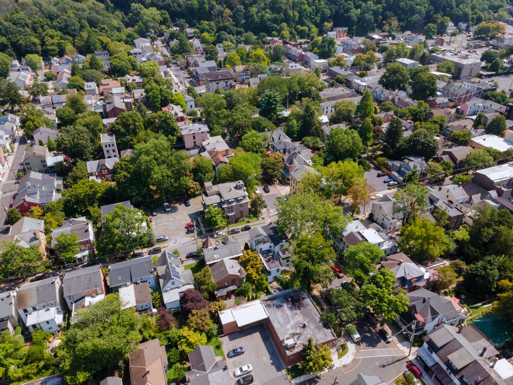 Aerial view of a charming, tree-lined town with historic buildings nestled among lush greenery.