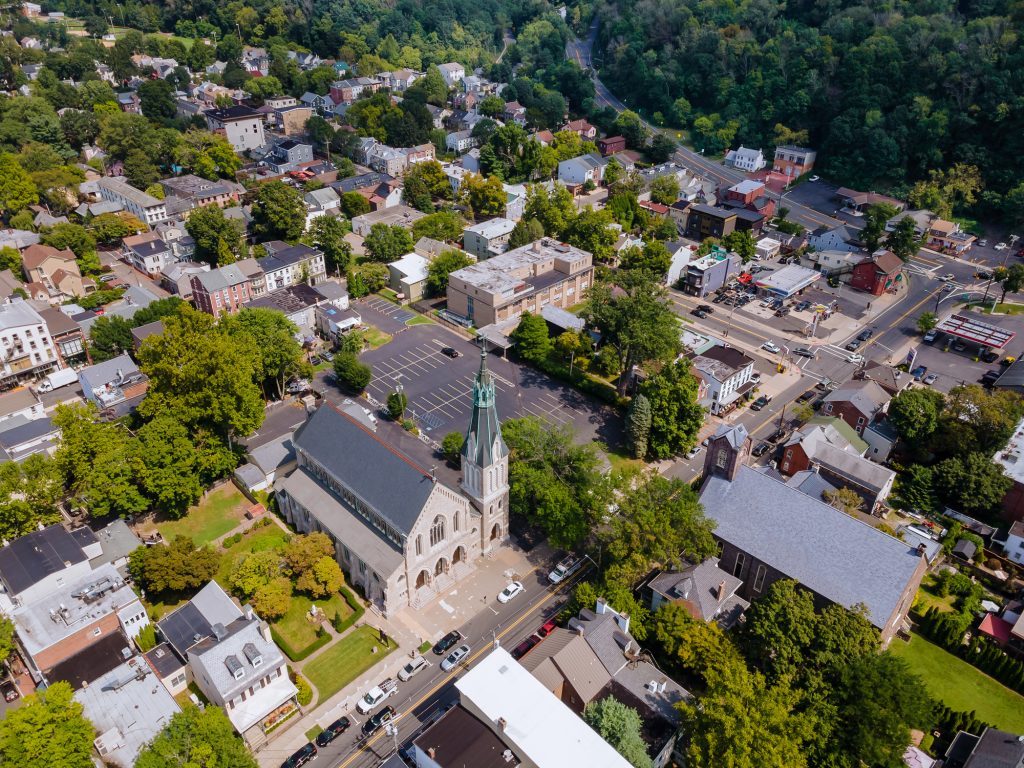 Aerial view of a quaint town with a prominent church surrounded by lush greenery and charming homes.