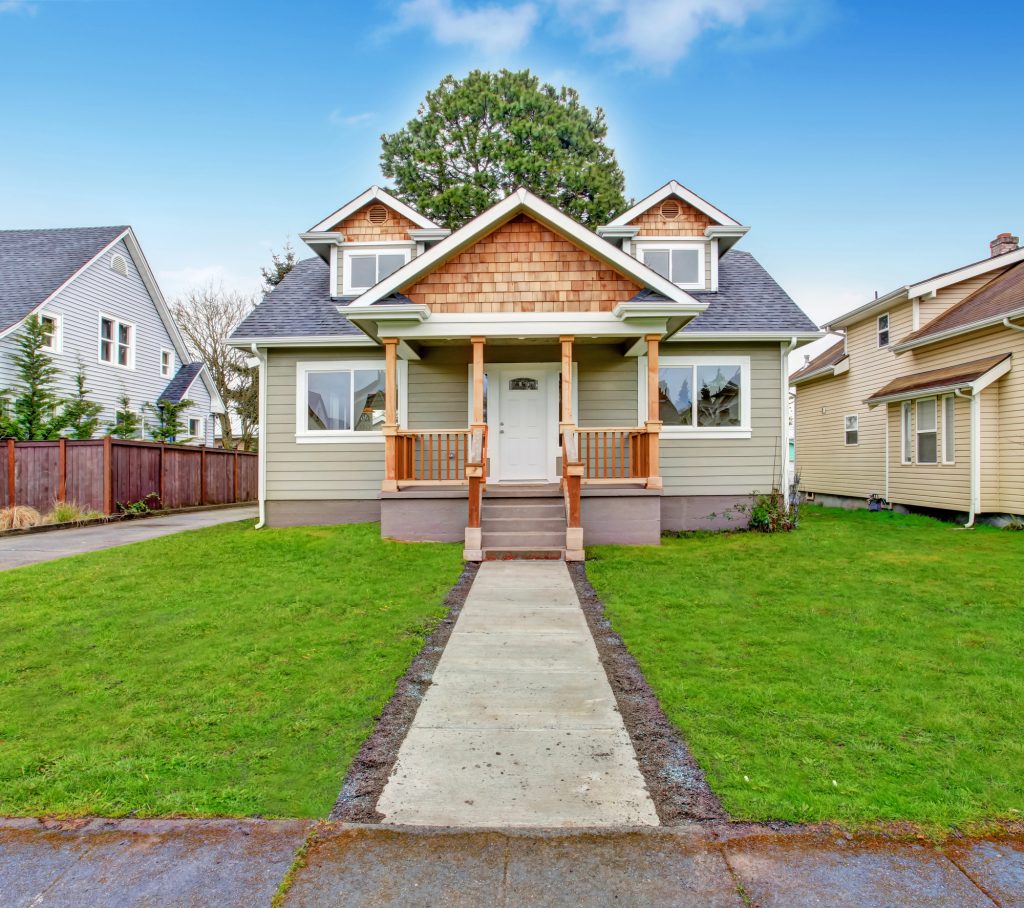 Charming Craftsman home with a welcoming front porch and bright green lawn.