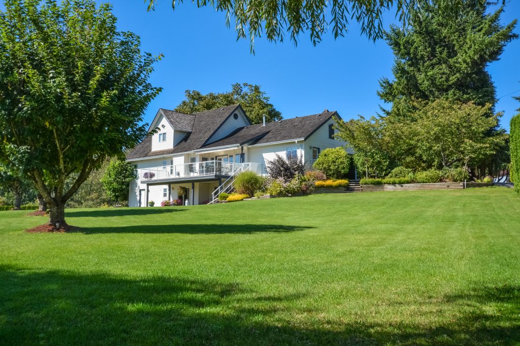 Charming countryside home surrounded by lush greenery and bright blue skies.