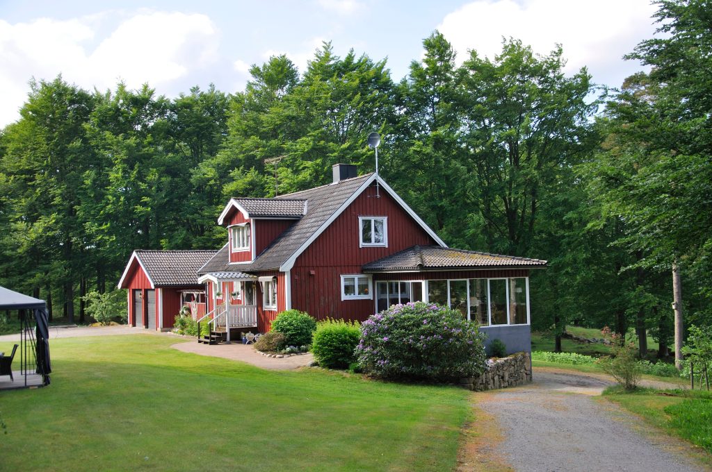 Charming red country house nestled in lush greenery.