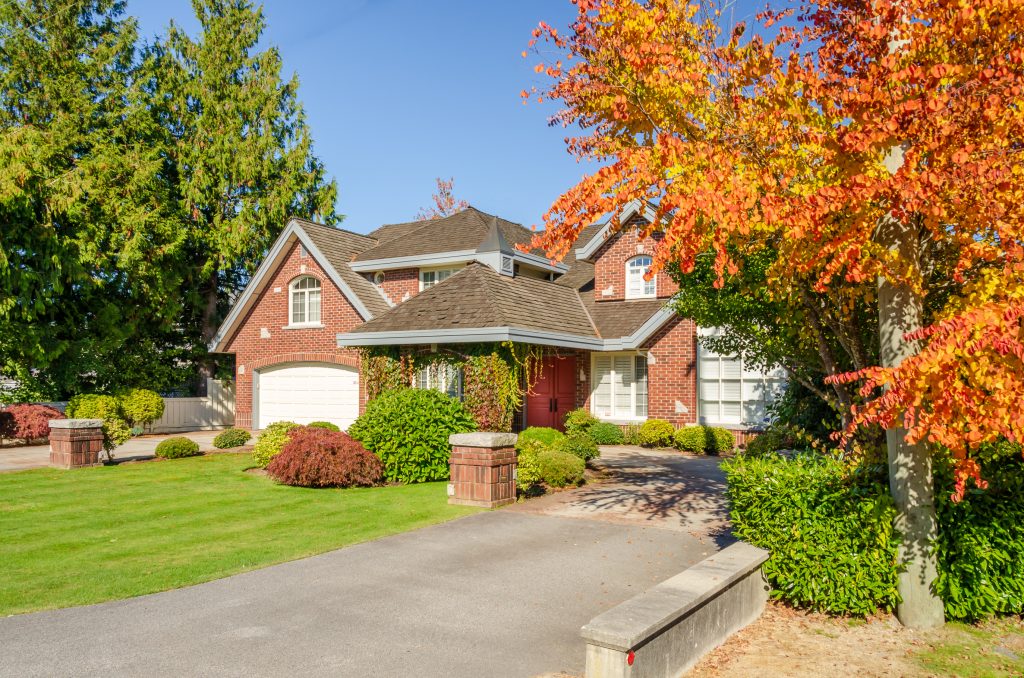 Charming brick home surrounded by vibrant autumn foliage.