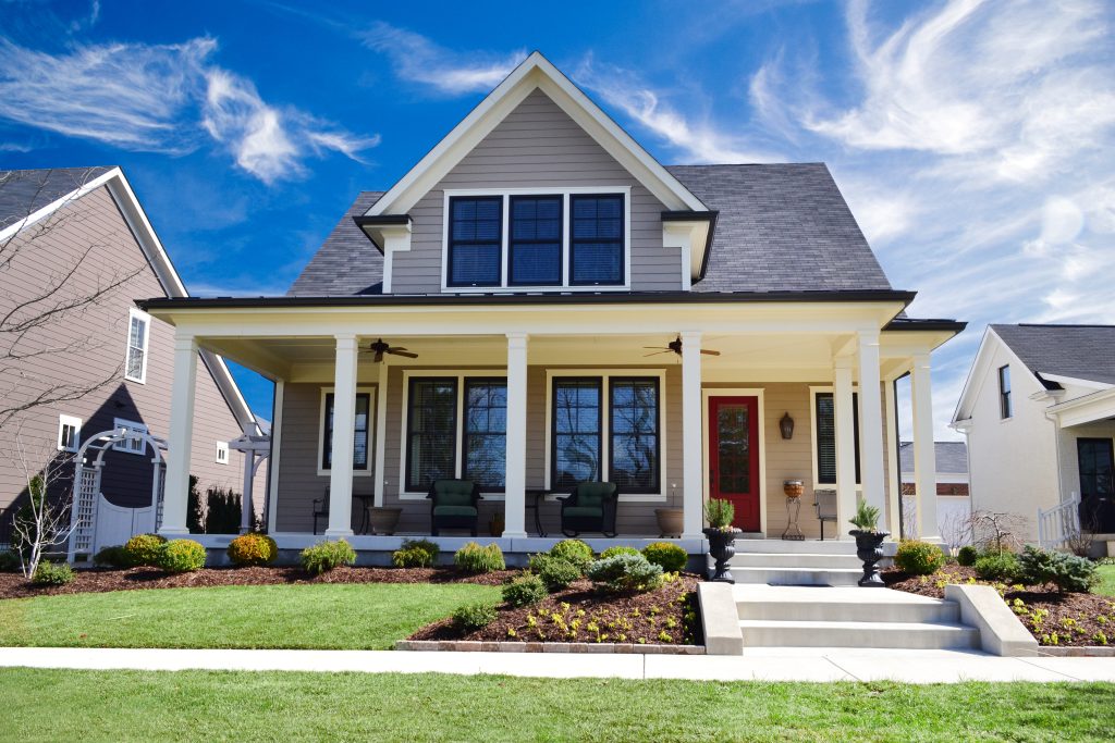 Charming suburban home with a welcoming porch on a bright, sunny day.