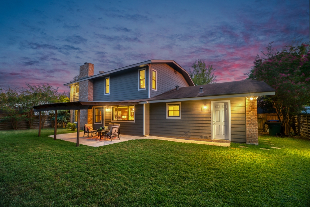 Serene twilight at a beautiful two-story suburban home with a cozy backyard patio.