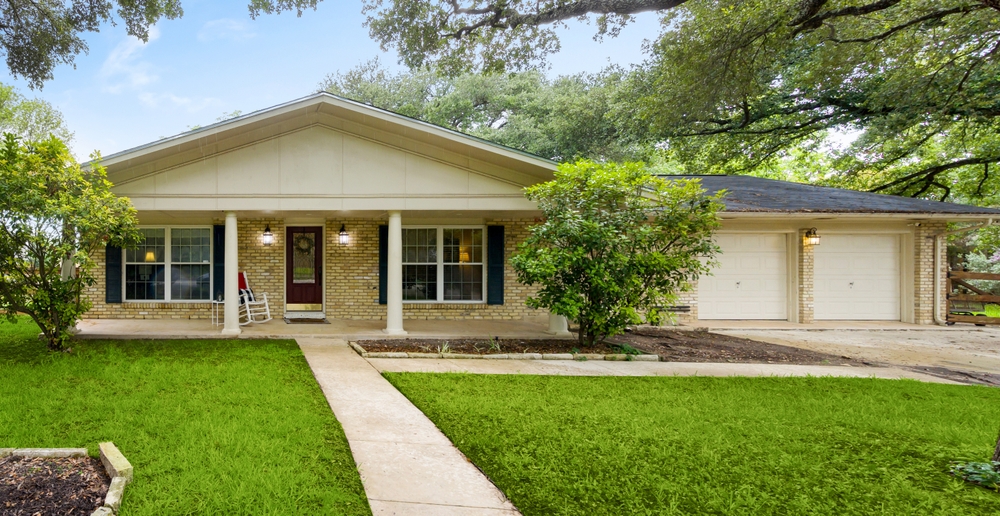 Charming single-story home with a welcoming front porch and lush greenery.