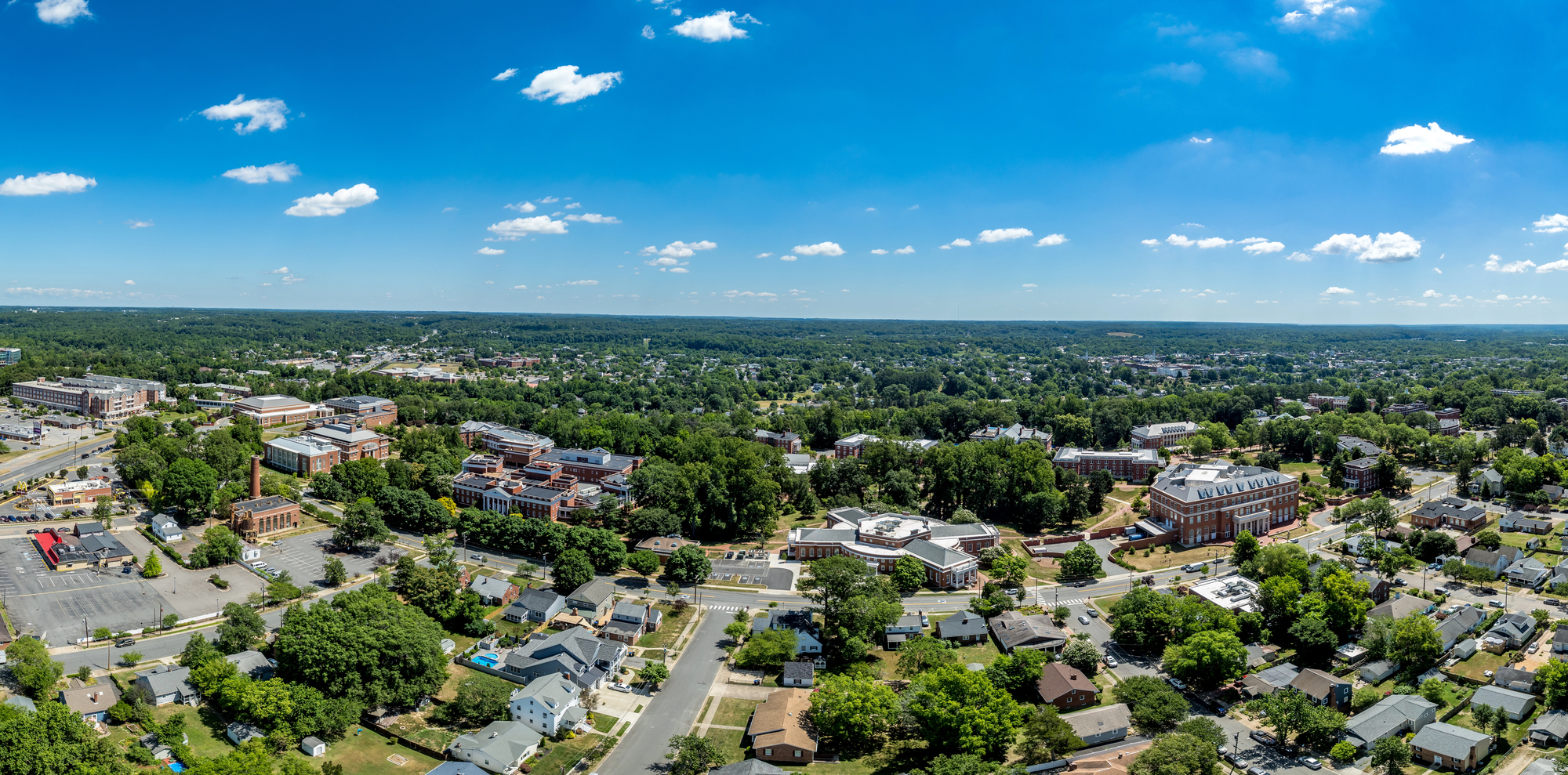 Aerial view of Virginia State University's picturesque campus surrounded by lush greenery under a clear blue sky.