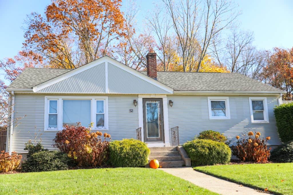 A cozy suburban home embraces the colors of autumn, with a lone pumpkin welcoming visitors.