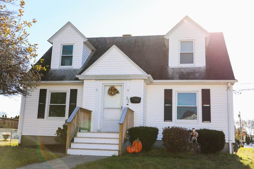Charming Cape Cod style home adorned with autumn pumpkins.