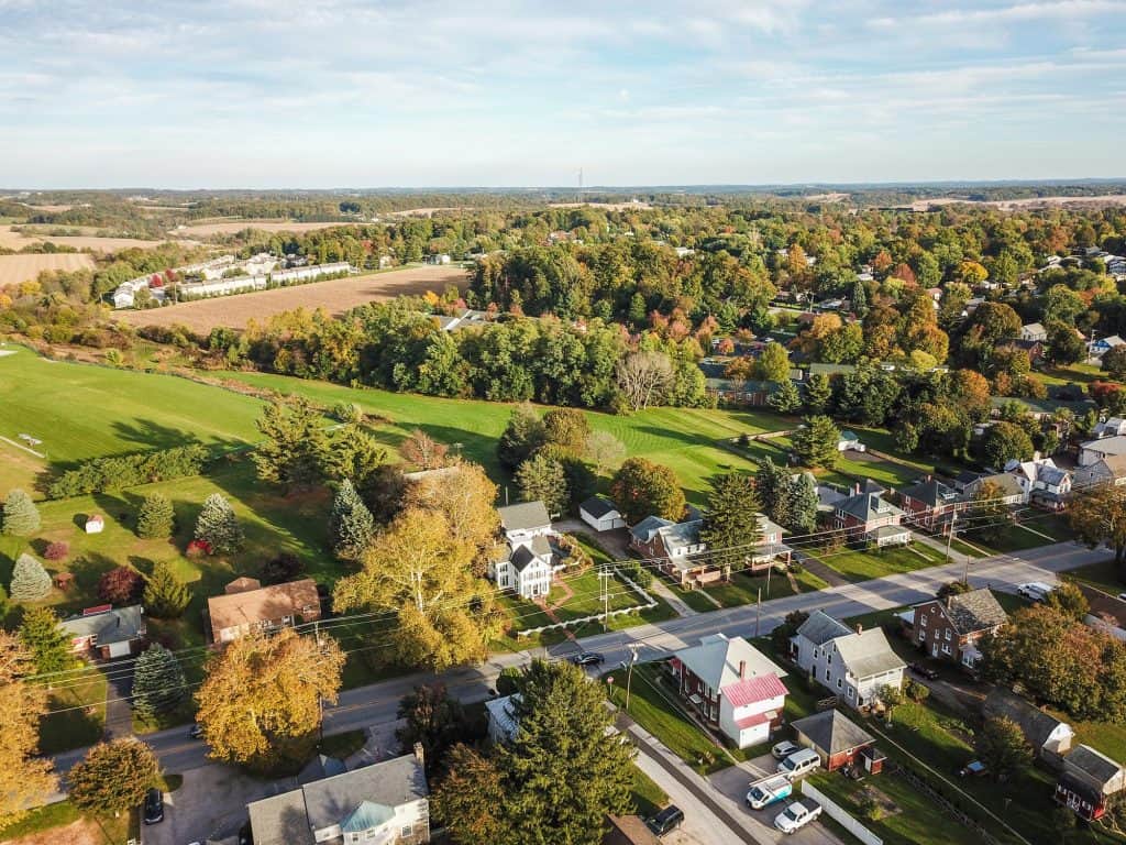 A charming aerial view of a peaceful countryside neighborhood, surrounded by vibrant greenery and sprawling farmland.