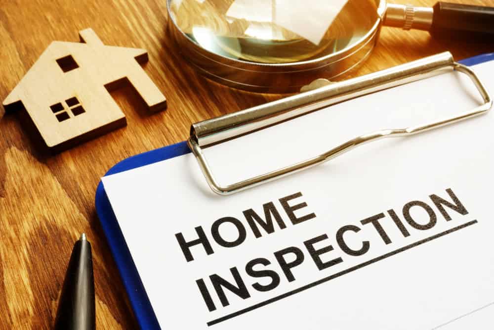 Preparing for a home inspection: clipboard, magnifying glass, and model house set the scene for property evaluation.