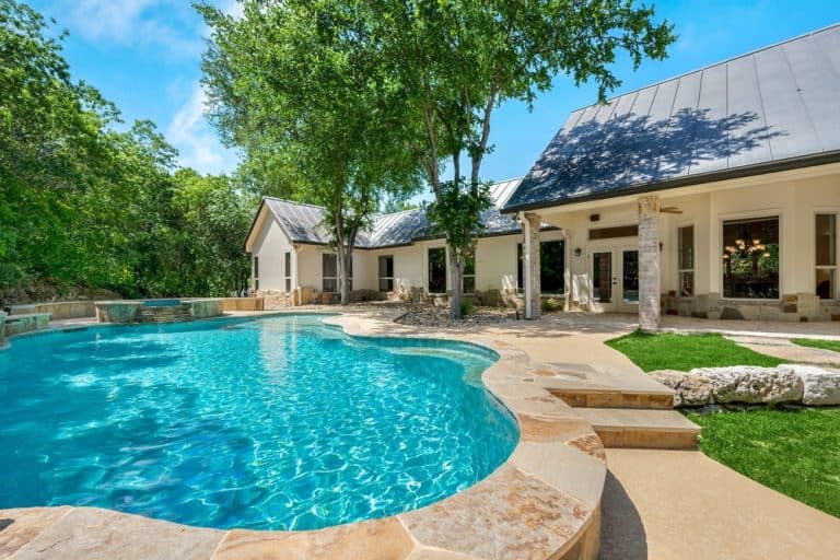 Relax by the serene poolside of this luxurious home, surrounded by lush greenery and elegant architecture.