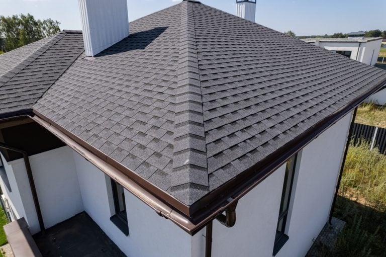 Modern home with sleek asphalt shingle roofing and clean lines, set against a serene backdrop.
