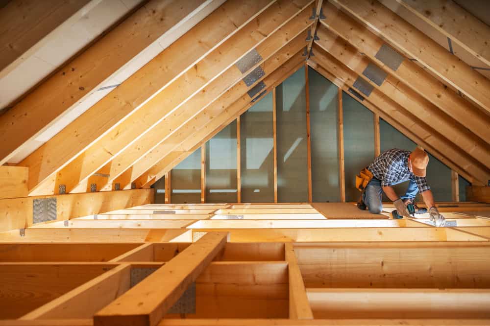 Focused craftsman at work inside a sunlit attic, bringing precision and care to every beam.