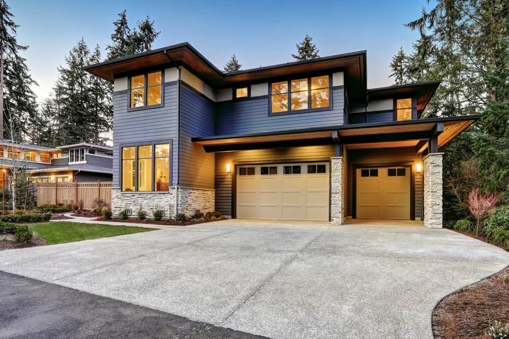 Modern elegance meets nature—stunning contemporary home with warm lighting, sleek design, and a serene wooded backdrop.