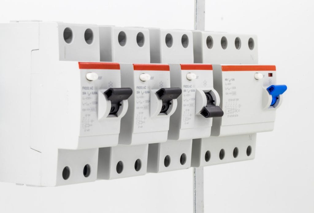 An electrician uses a screwdriver to adjust wiring inside a circuit breaker panel.