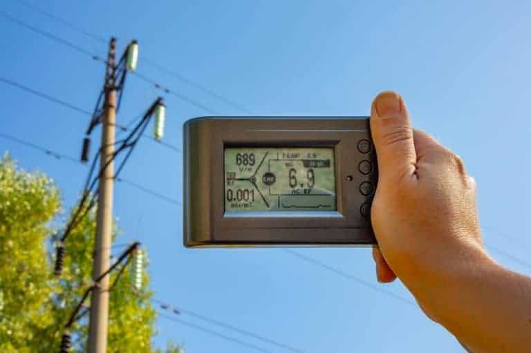 Measuring electromagnetic field (EMF) levels near a power line on a sunny day.