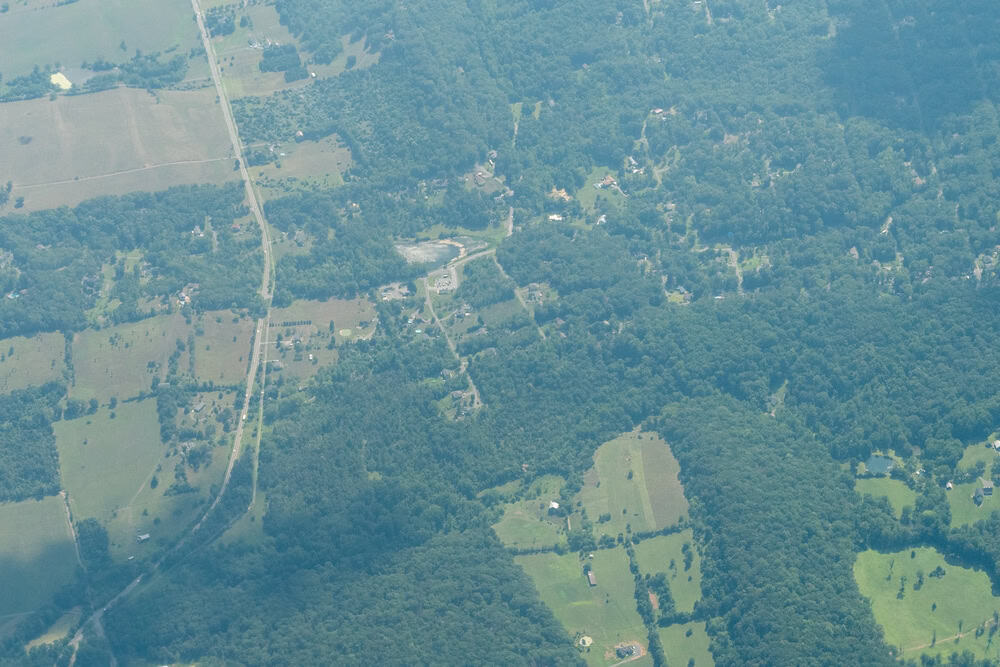 Aerial view of a lush, green landscape with winding roads and scattered fields.