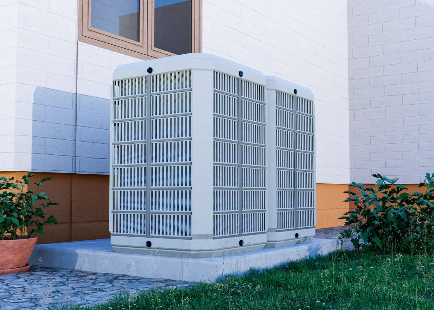 Two large central air conditioning units sit outside a house on a concrete pad, surrounded by garden plants and green grass.