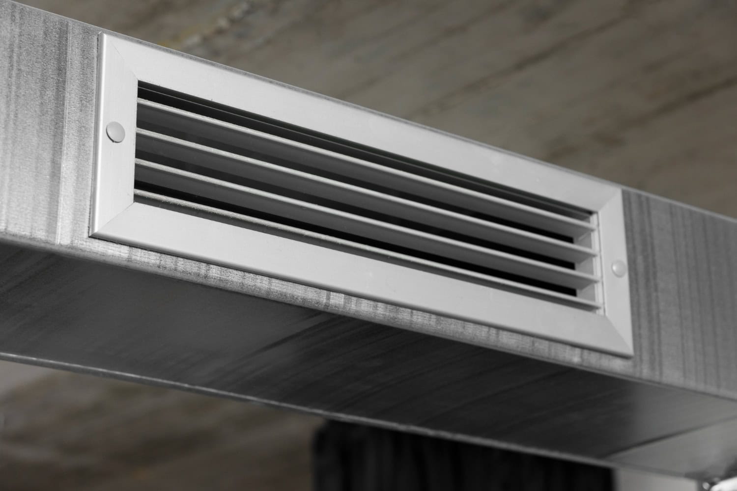 Close-up of a modern metal air vent installed in a ceiling, providing ventilation for indoor climate control.