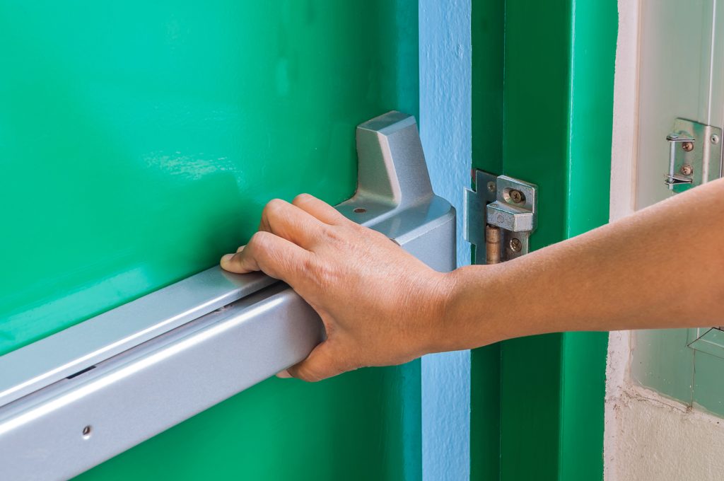 Hand is pushing/opening the emergency fire exit door