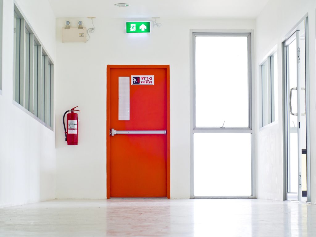 A bright hallway with a vivid red emergency exit door.
