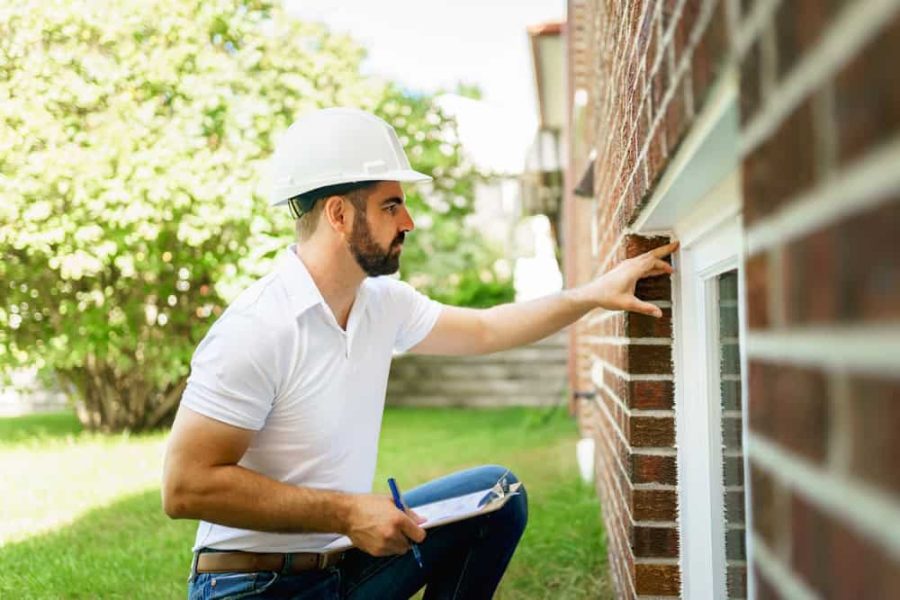 A home inspector inspects a brick wall, clipboard in hand, ensuring quality and precision.